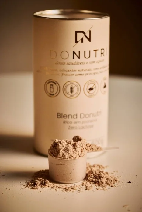 Lata do Blend proteico DONUTRI com uma porção de proteína em pó ao lado