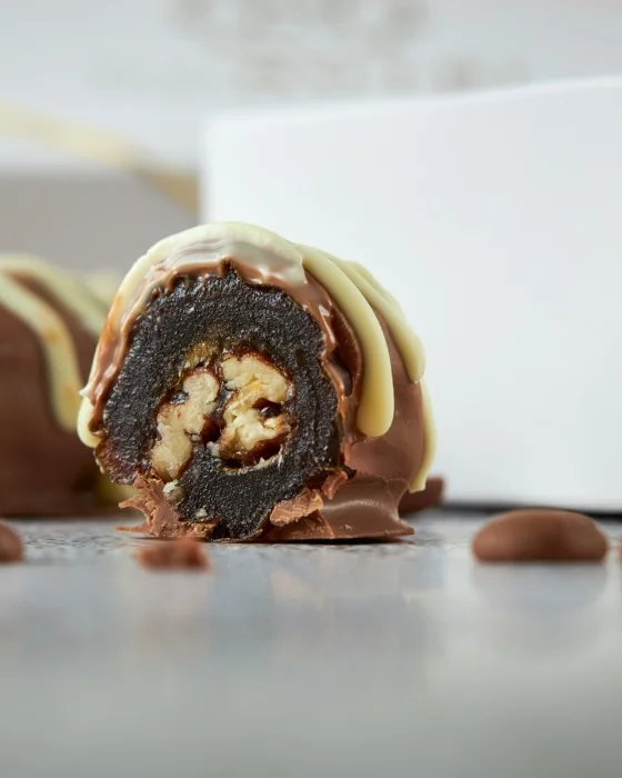Tâmara jumbo DONUTRI cortada, recheada com noz pecã e coberta de chocolate